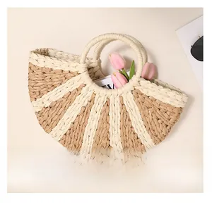 Detail showing the semi-circular woven straw handbag with beige and tan radial pattern