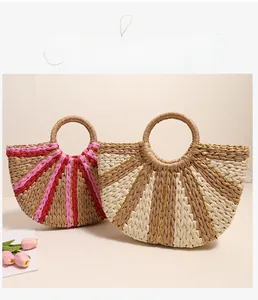 Detail of handmade striped straw woven bag with gold thread and circular handles
