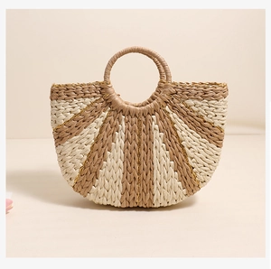 Detailed view of bicolor straw bag featuring golden threads and circular handles