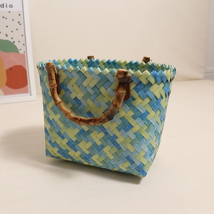 Blue and green checkered hand-woven straw bag with natural bamboo handles for beach use