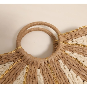 Detail of handmade straw bag with ring handle and gold wire woven accents