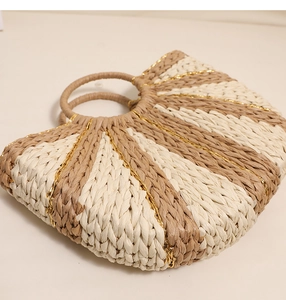 Detailed macro view of woven straw bag showing golden thread and striped half-moon pattern
