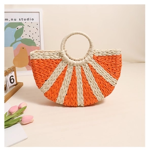 Detail of a half-moon woven straw handbag with orange radial stripes and ring handles
