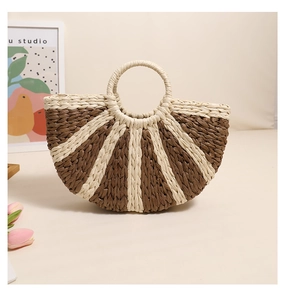 Detailed radial weave pattern of the semi-circular straw handbag with ring handles