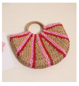 Detail of a semi-circular straw bag with pink striped patterns and a round woven handle