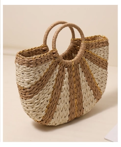 Detailed close-up of semi-circular woven straw bag with golden thread and striped texture