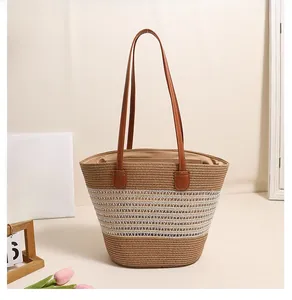 Close-up of bohemian striped straw tote bag with brown leather handles and woven texture