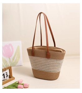 Detailed texture of the woven straw tote bag with brown PU leather straps on a desk
