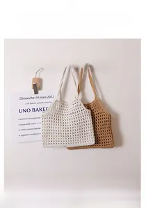 Détail de sacs bandoulière en maille de coton tissé crème et beige sur crochets bois
