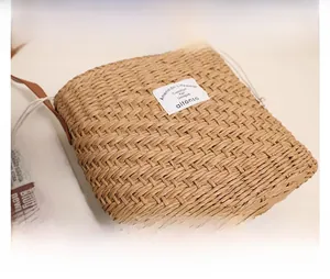 Close-up of a woven straw shoulder bag featuring a white fabric label and brown strap