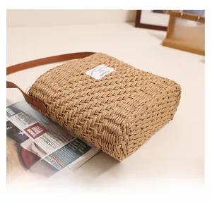 Detail view of straw woven shoulder bag showing natural texture and leather strap