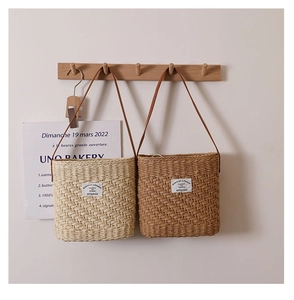 Detail of square straw shoulder bags in beige and brown with thin leather straps