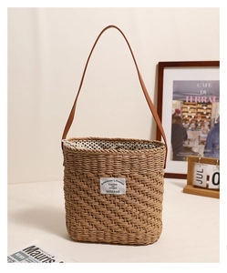 Close-up of square straw tote bag with leather strap and American Lifewear patch detail