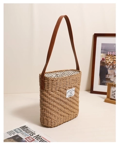 Detail of square straw bag with brown leather strap and polka dot drawstring lining