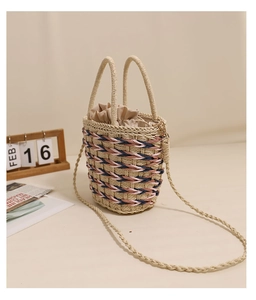 Detail view of woven straw bucket bag with blue and pink patterns and drawstring liner