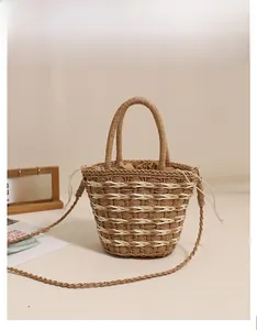 Detail of coffee brown woven straw bucket bag with drawstring closure and shoulder strap