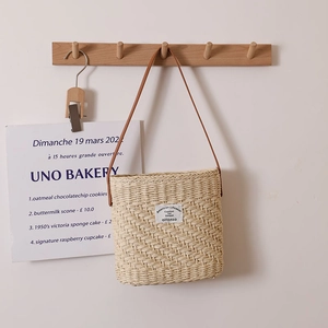 Minimalist square straw shoulder bag with leather strap hanging on wooden wall hook