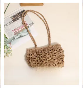 Detail of hollow floral pattern on a handmade khaki woven straw shoulder beach bag