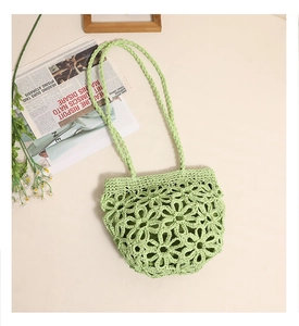 Detail of lime green hand-woven straw bag with hollow flower patterns and braided strap