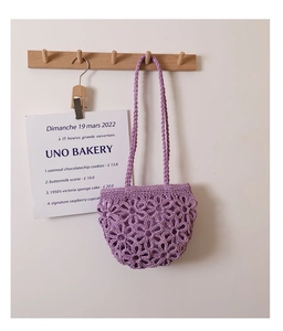 Close-up of a purple hand-knitted crochet bag with intricate hollow flower patterns