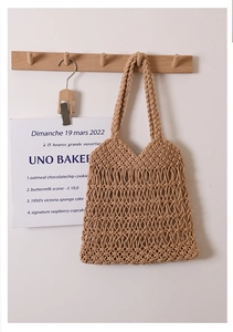 Dettaglio della trama a rete traforata e dei manici tondi di una borsa da spiaggia beige