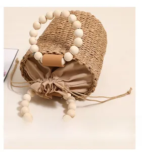 Detail of woven straw bucket bag featuring round wooden bead handles and drawstring liner