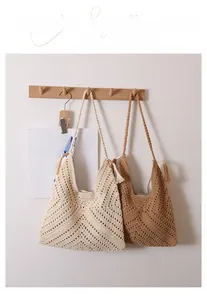 Close-up of handmade crochet hollow triangle bag with tassel detail and woven strap