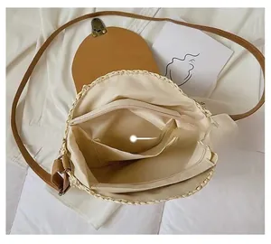 Detail of round straw crossbody bag interior with zip pocket and brown leather flap
