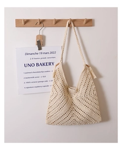 Detail of beige crochet shoulder bag featuring fringe tassel and intricate hollow pattern