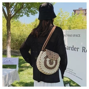 Outdoor model display of round woven straw crossbody bag with geometric print flap