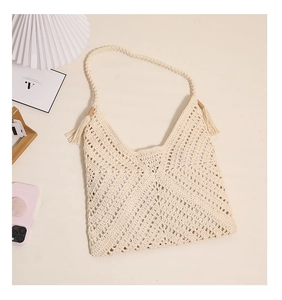 Detail of cream woven shoulder bag with V-shaped hollow pattern and tassel accents