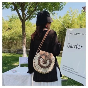 Detail of round straw crossbody bag with geometric pattern flap and brown leather strap