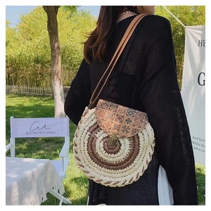 Detail of round straw crossbody bag with ethnic print leather flap and metal buckle