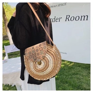 Close-up of circular woven straw bag featuring floral cork lid and metallic buckle