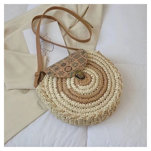 Detail of round straw bag with floral print lid, metal clasp, and brown leather strap