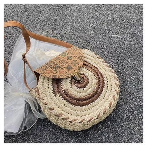 Detailed view of round straw crossbody bag with ethnic print flap and metal clasp