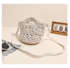 Detail of a beige woven cotton bucket bag with rounded top handles and a long strap