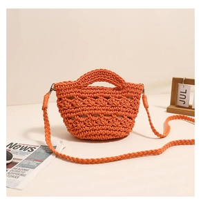 Detail of orange crochet crossbody bag featuring hollow woven texture and long strap