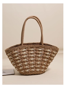 Detailed close-up of geometric two-tone woven straw tote bag with brown fabric lining