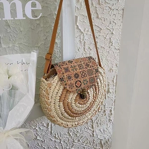 Round woven straw crossbody bag with floral cork lid and adjustable leather strap