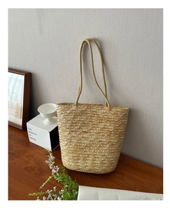 Close-up of minimalist straw woven shoulder bag on a wooden table for summer beach trips