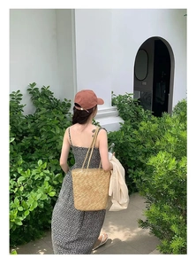 Outdoor shot of a summer outfit with floral dress and large straw tote bag for beach vacations