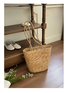 Detail of hand-woven straw tote bag with magnetic closure and natural texture finish