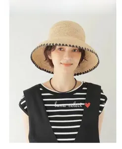 Detailed weave of beige raffia sun hat featuring black decorative trim on the brim