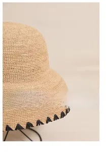 Close-up of raffia sun hat featuring hand-embroidered black wavy edge detailing