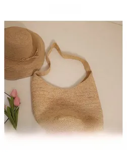 Detailed close-up of intricate crochet weave pattern on a beige raffia shoulder beach bag