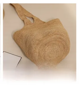 Detailed view of the reinforced round base of the woven raffia straw shoulder bag
