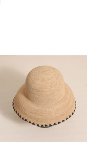 Close-up of raffia sun hat with tight weave texture and black wavy edge detailing