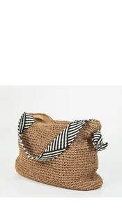 Detail of hand-woven straw shoulder bag with striped wide strap and knotted bow design