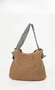 Detail of handwoven straw tote bag with stylish black and white striped fabric handles